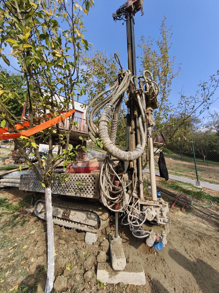 Vrtná souprava s vrtnou věží na zahradě, vedle ovocný strom
